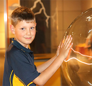 Lutheran Education home page insider insights image. Young boy with hands on a glass electromagnetic ball